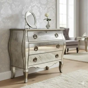 A Venetian-style mirrored chest of drawers with an antiqued finish and curved legs against patterned wallpaper.
