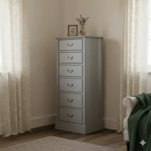 A slim grey shabby chic tallboy chest of drawers tucked into a cosy cottage bedroom corner.