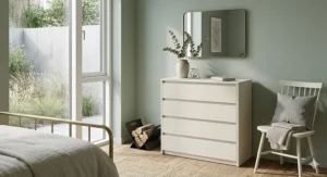 A vintage-style distressed cream chest of drawers with ornate metal handles in a rustic country cottage bedroom.