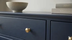Detail of the wood grain texture on a deep navy blue painted chest of drawers.
