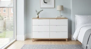 A photorealistic 4K styled photograph featuring a minimalist Scandinavian-style two-tone chest of drawers with white drawers, a natural oak top, and tapered legs.