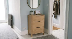 A compact narrow chest of drawers placed in a hallway for entryway storage.
