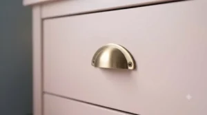 Decorative gold handles on a matte pink chest of drawers.