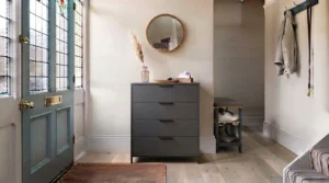 A space-saving slim chest of drawers styled with a mirror and lamp in an urban terraced house entrance.