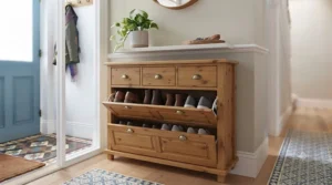 A traditional solid pine shoe organiser chest with panelled drawers in a classic British cottage hallway.