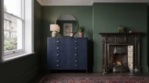 Eclectic bedroom styling combining a period fireplace with a modern statement chest of drawers.