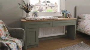 Low height under window chest of drawers in a neutral nursery with children's books on top