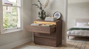Chest of drawers with built-in lighting switched on in a dimly lit room, highlighting practical nighttime visibility.