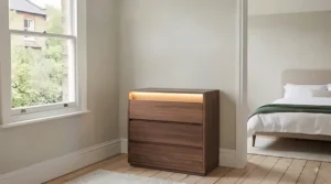 Close-up of warm white integrated LED strip lighting fitted beneath the top surface of a modern chest of drawers.