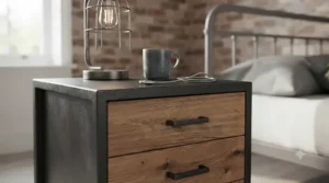A close-up perspective looking into the open bottom drawer of the industrial bedside table, showcasing a tidy arrangement of coiled charging cables, earbuds, and a small multi-compartment organiser.